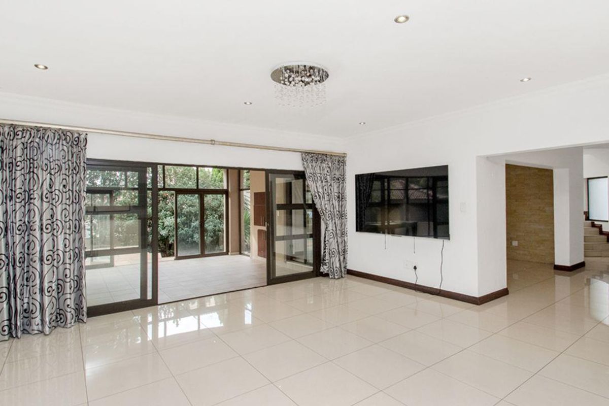 Spacious living area featuring large sliding glass doors leading to a covered patio, polished tile flooring, and recessed ceiling lighting.