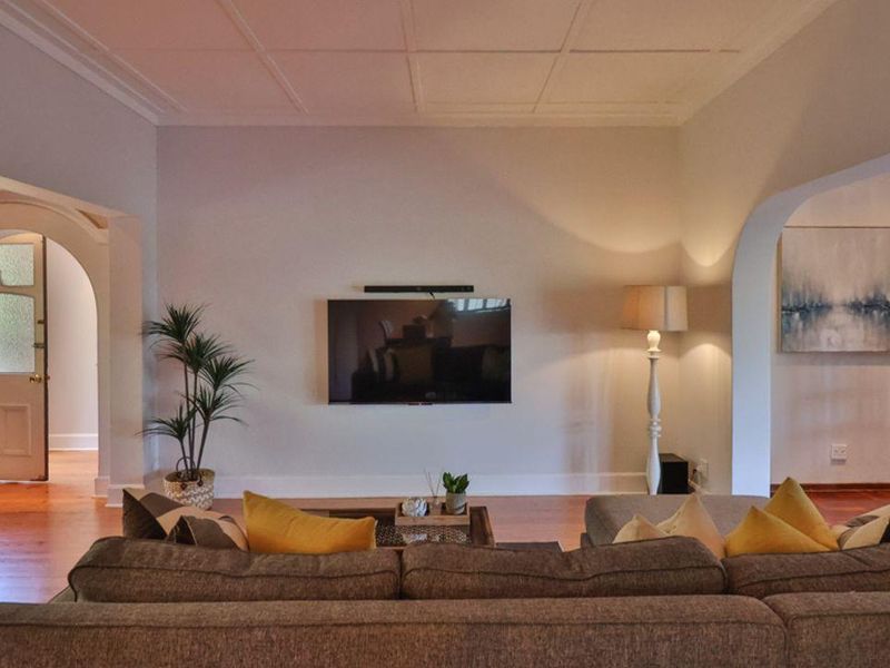 A spacious living room featuring arched doorways, timber flooring, and a coffered ceiling, creating a warm and inviting atmosphere.