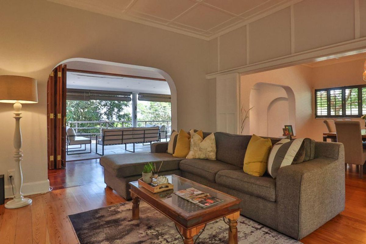 Spacious living area featuring polished timber flooring, decorative ceiling detailing, and seamless flow to an expansive covered patio through large arched openings.