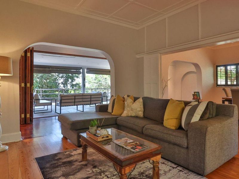 Spacious living area featuring polished timber flooring, decorative ceiling detailing, and seamless flow to an expansive covered patio through large arched openings.
