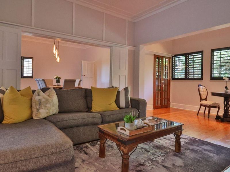Spacious open-plan living area featuring polished timber flooring, classic wall paneling, and elegant French doors leading to an adjoining dining space.