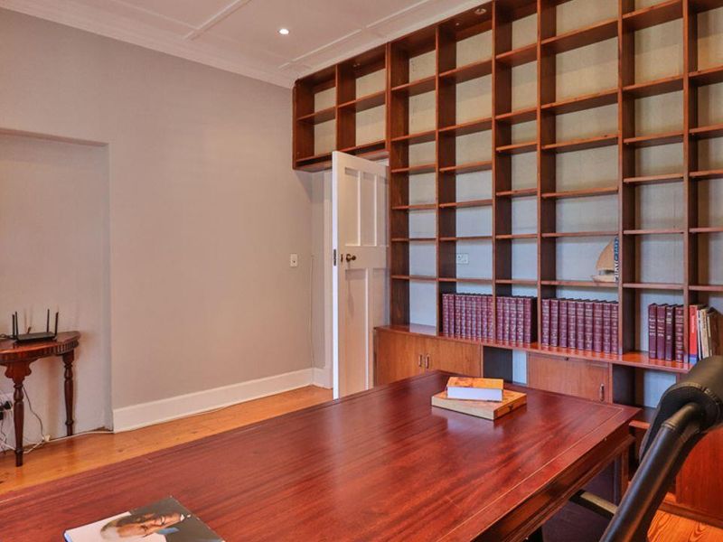 A dedicated home office featuring extensive floor-to-ceiling built-in wooden shelving and cabinetry, providing ample storage and a professional workspace environment.