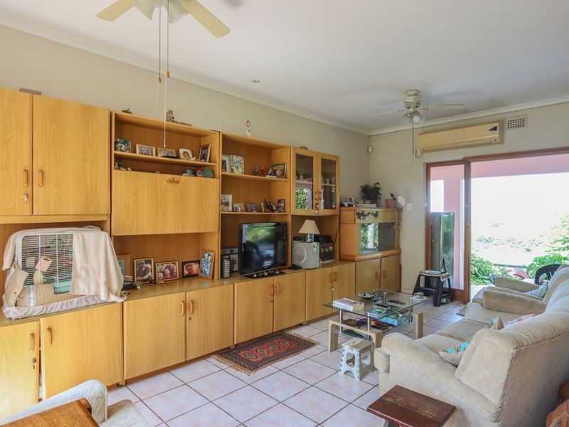 A living room featuring tiled flooring, a ceiling fan, and a split-system air conditioner, with direct access to an outdoor area via sliding glass doors.