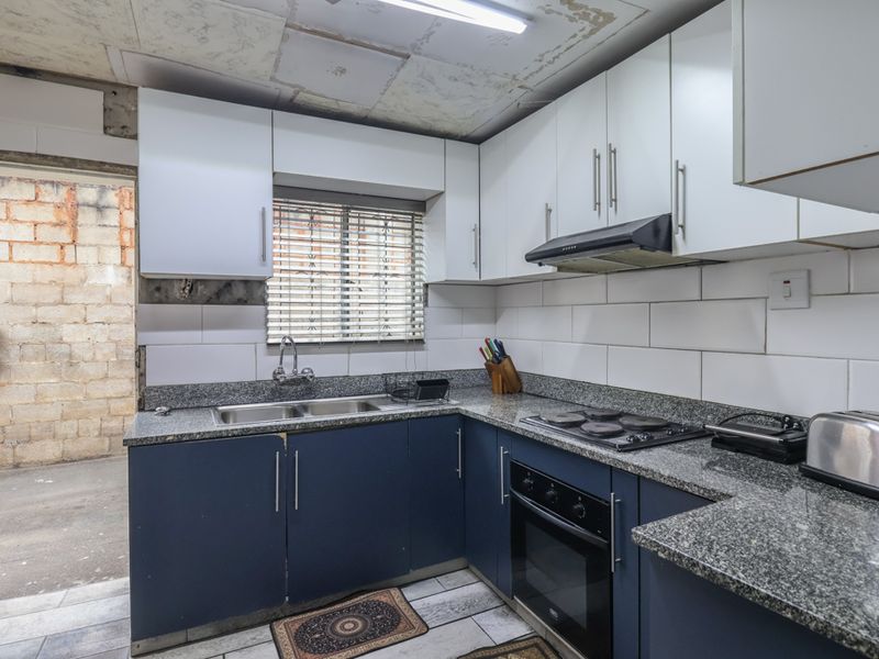 Compact kitchen featuring granite countertops, built-in oven, and hob. The space requires ceiling repairs and finishing touches to complete the aesthetic.