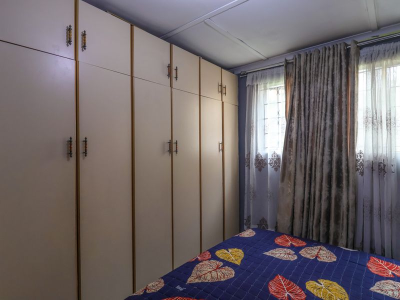 Bedroom featuring extensive floor-to-ceiling built-in cupboards and a window with security bars.