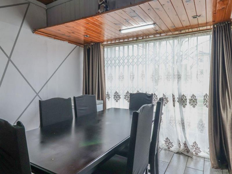 Dining area featuring tiled flooring, a timber-paneled ceiling, and a security gate over the window.