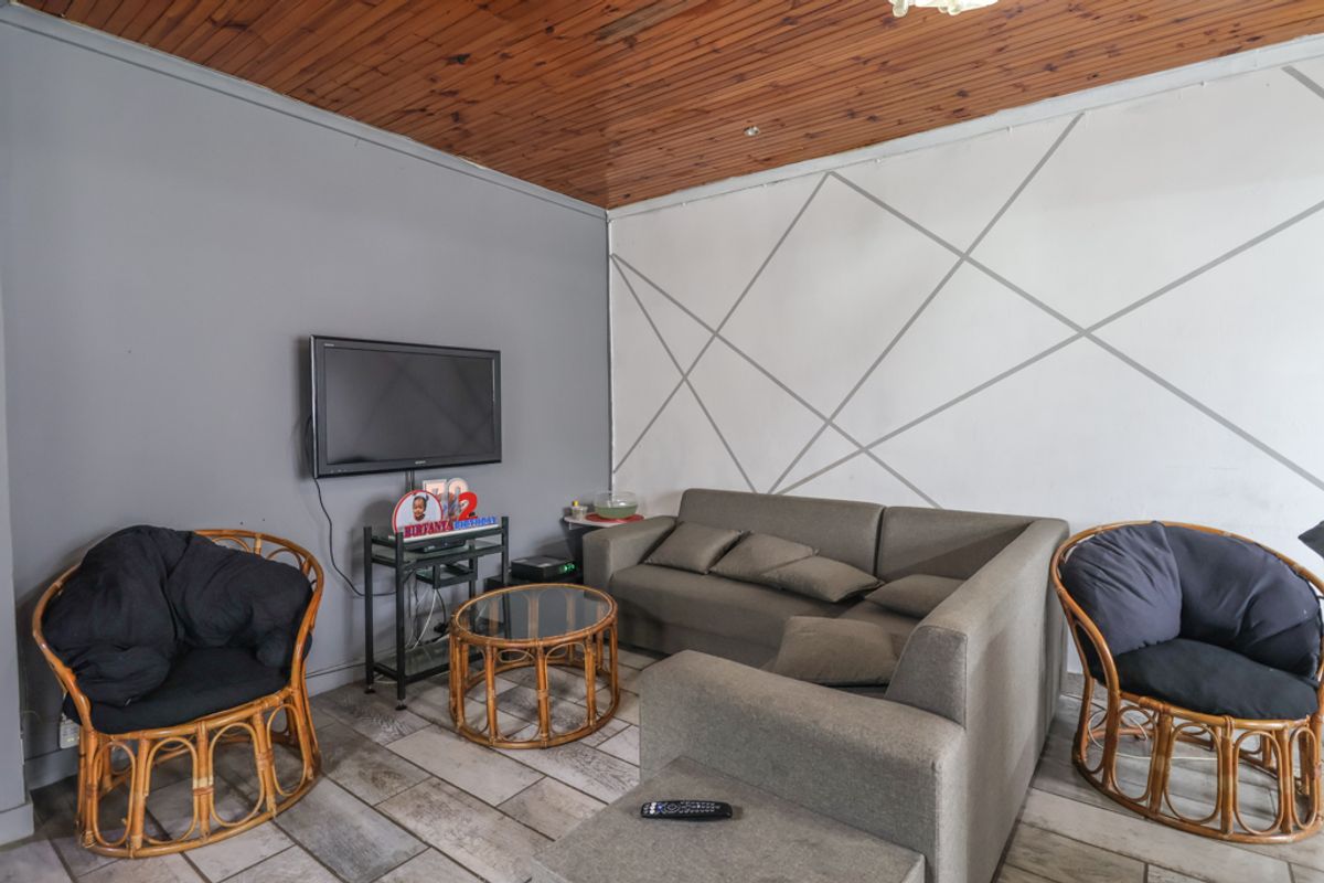 A living room featuring a timber-clad ceiling and tiled flooring, offering a functional space with potential for cosmetic updates.