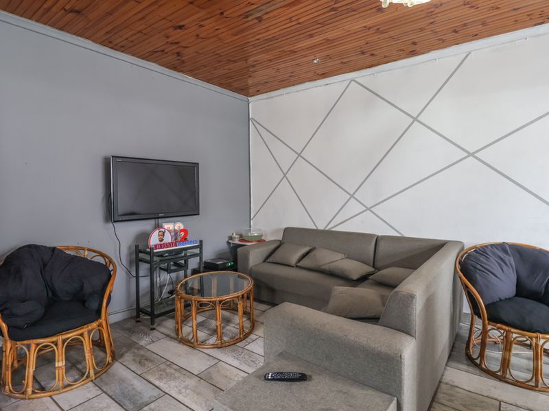 A living room featuring a timber-clad ceiling and tiled flooring, offering a functional space with potential for cosmetic updates.