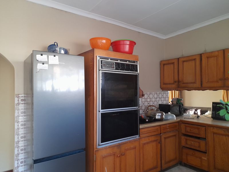 A functional kitchen featuring traditional wooden cabinetry, a built-in double oven, and a patterned tile backsplash with laminate countertops.