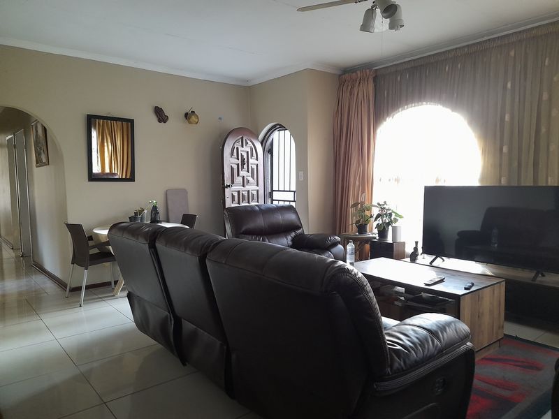 A living room featuring tiled flooring, an arched window, and an open archway leading to other areas of the home.