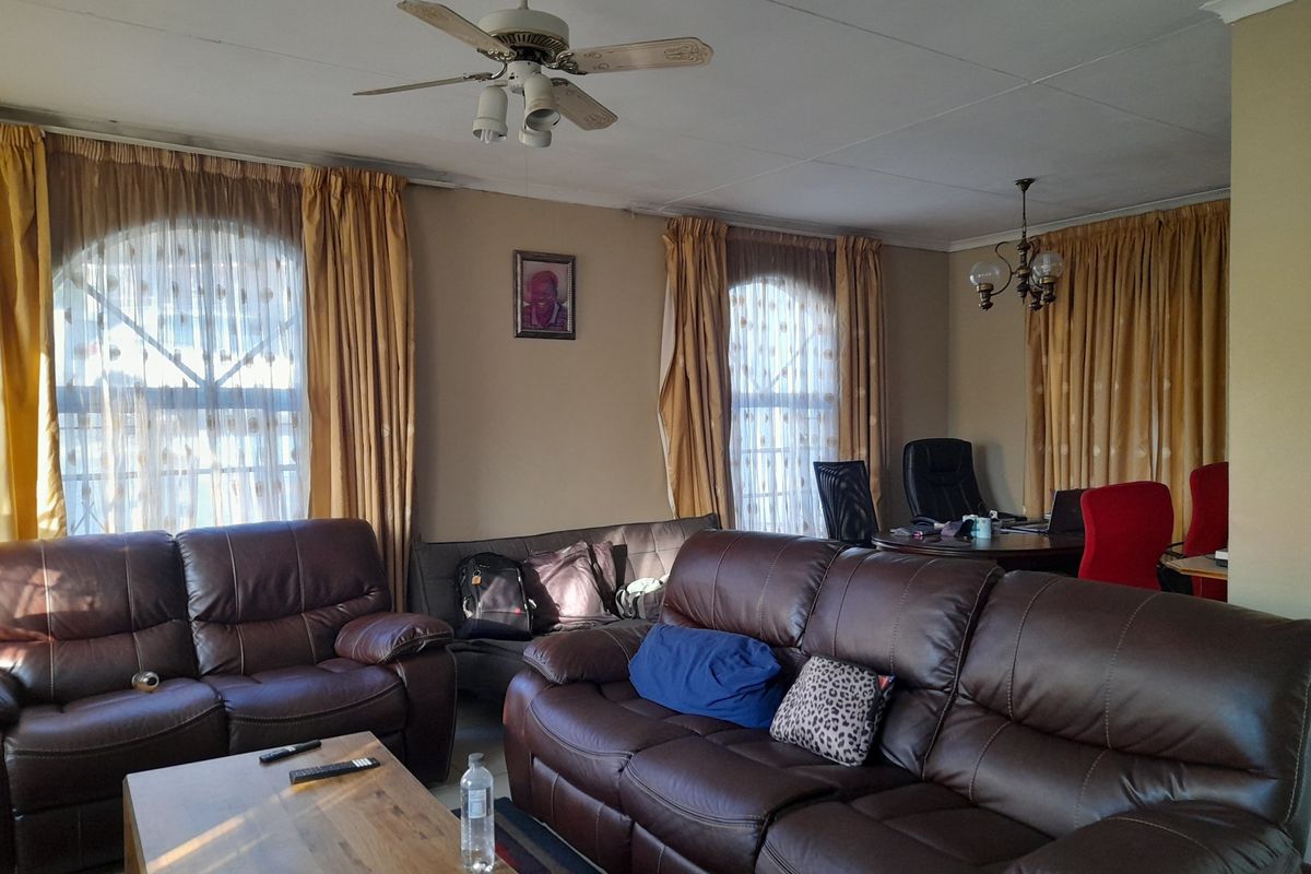 Spacious living area featuring arched windows, a ceiling fan, and coved ceilings, offering a versatile layout for relaxation and home office use.