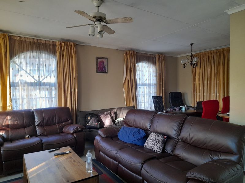 Spacious living area featuring arched windows, a ceiling fan, and coved ceilings, offering a versatile layout for relaxation and home office use.