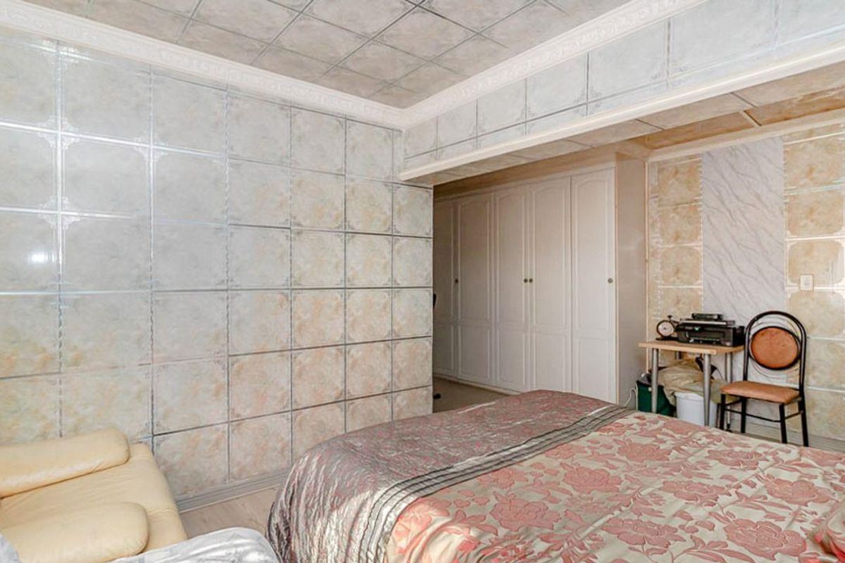 Bedroom featuring built-in wardrobe storage and tiled wall and ceiling finishes.
