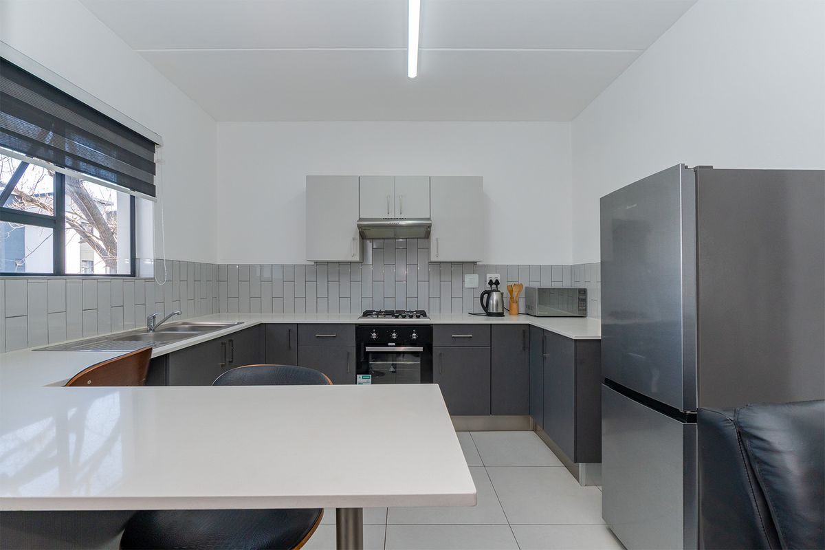 Modern kitchen featuring grey cabinetry, white countertops, subway tile backsplash, built-in oven, gas hob, and stainless steel extractor fan.