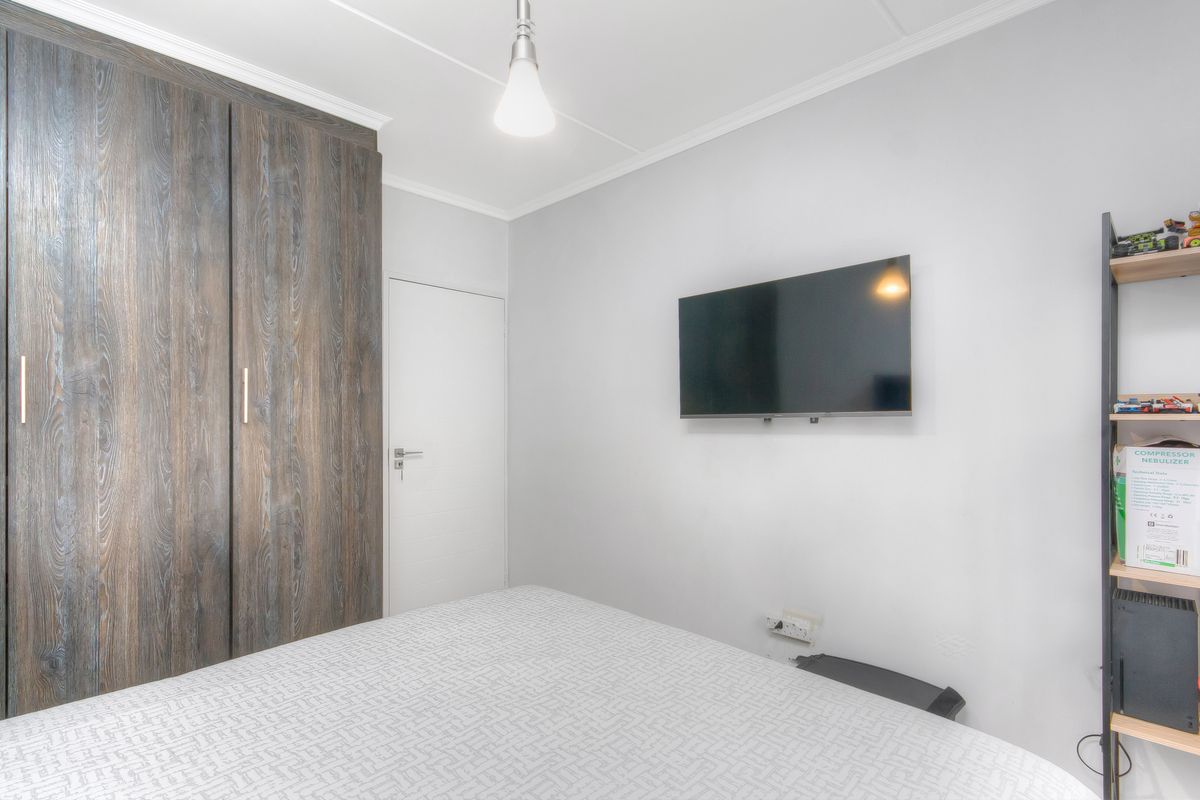 A bedroom featuring built-in wooden cabinetry and a wall-mounted television, providing a functional and clean living space.