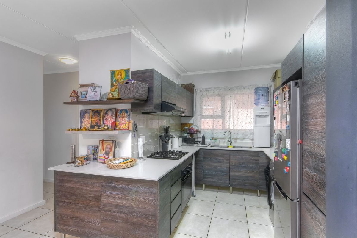 A functional kitchen featuring dark wood-grain cabinetry, white stone countertops, a built-in gas hob, and tiled flooring.