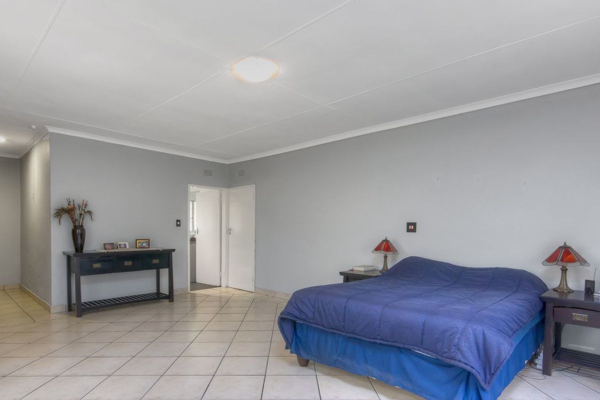 Spacious bedroom featuring neutral grey walls, tiled flooring, and a simple ceiling finish, providing a clean and functional living space.