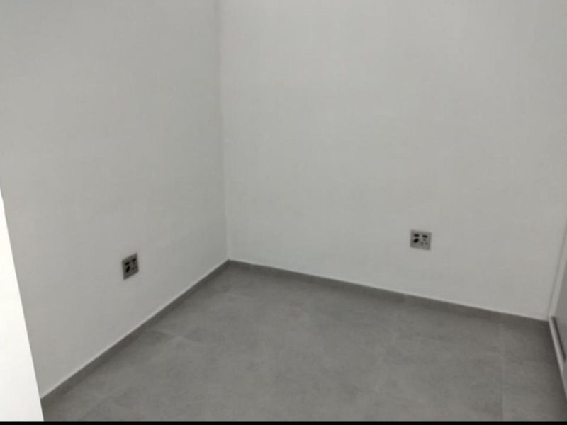 A clean, empty room featuring neutral tiled flooring and white walls, suitable for use as a bedroom or home office.