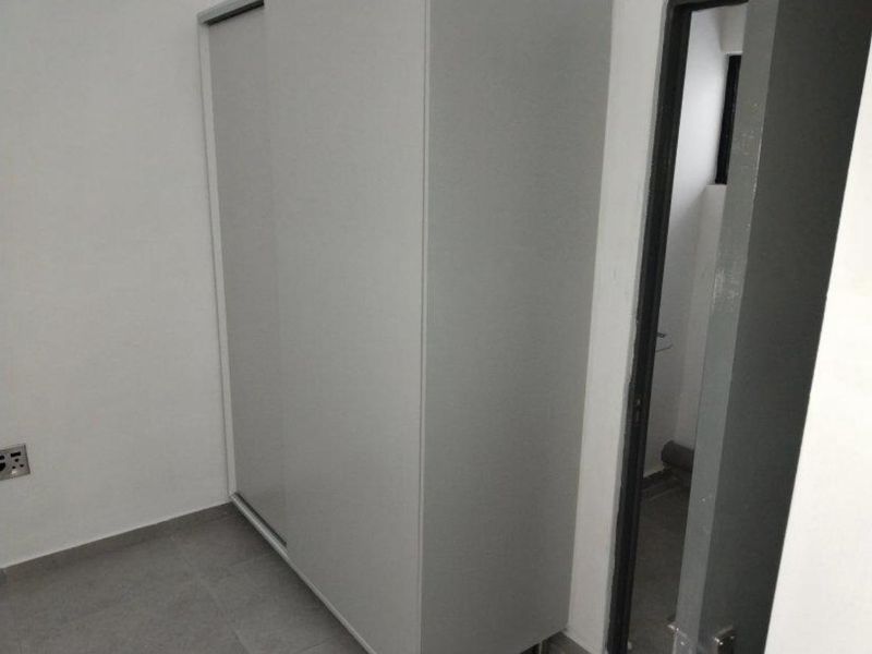 A clean, minimalist bedroom featuring neutral tiled flooring and a modern built-in sliding door wardrobe.