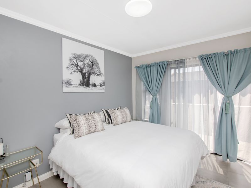 A well-maintained bedroom featuring tiled flooring, neutral grey walls, and a sliding glass door providing access to an outdoor area.