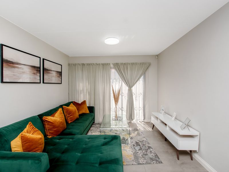 A well-maintained living room featuring neutral wall finishes, tiled flooring, and a sliding glass door providing access to the exterior.
