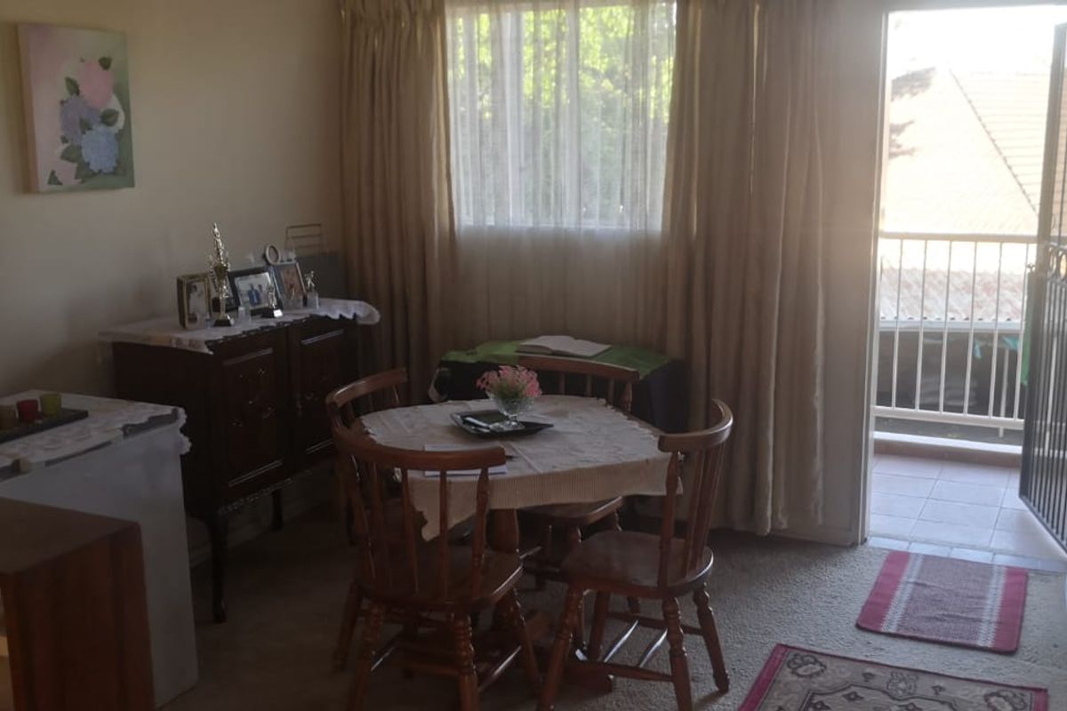 A living area featuring carpeted flooring and direct access to an outdoor balcony through a security gate.
