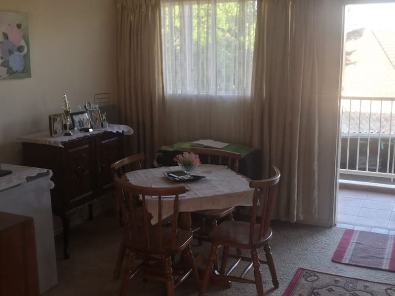 A living area featuring carpeted flooring and direct access to an outdoor balcony through a security gate.