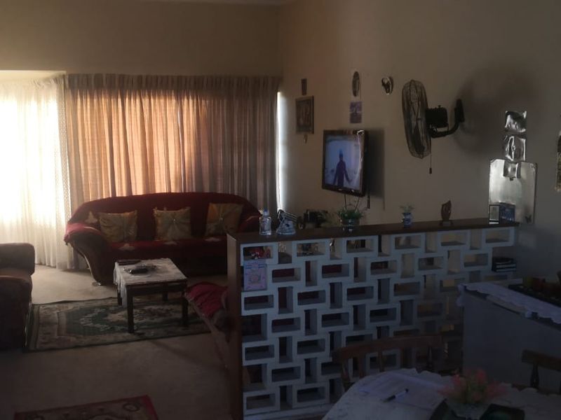 Open plan living and dining area featuring a decorative breeze block partition wall and large windows with curtain tracks.