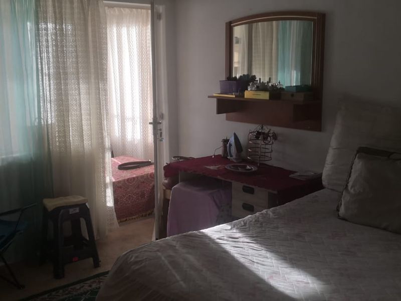 A bedroom featuring a built-in vanity mirror and direct access to an adjoining balcony area.
