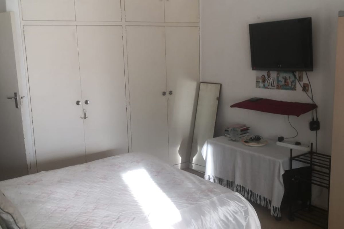 A bedroom featuring floor-to-ceiling built-in cupboards providing ample storage space.