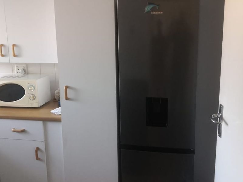 A compact kitchen area featuring laminate countertops, built-in cabinetry, and a tiled backsplash, providing functional storage and preparation space.
