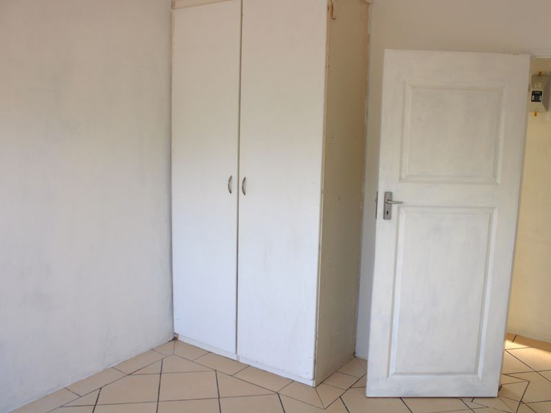 An empty bedroom featuring tiled flooring and a built-in cupboard, providing a blank canvas for personalization.