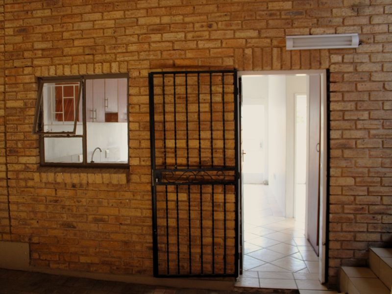 Entrance area featuring exposed brick walls, a security gate, and tiled flooring leading into the interior of the apartment.