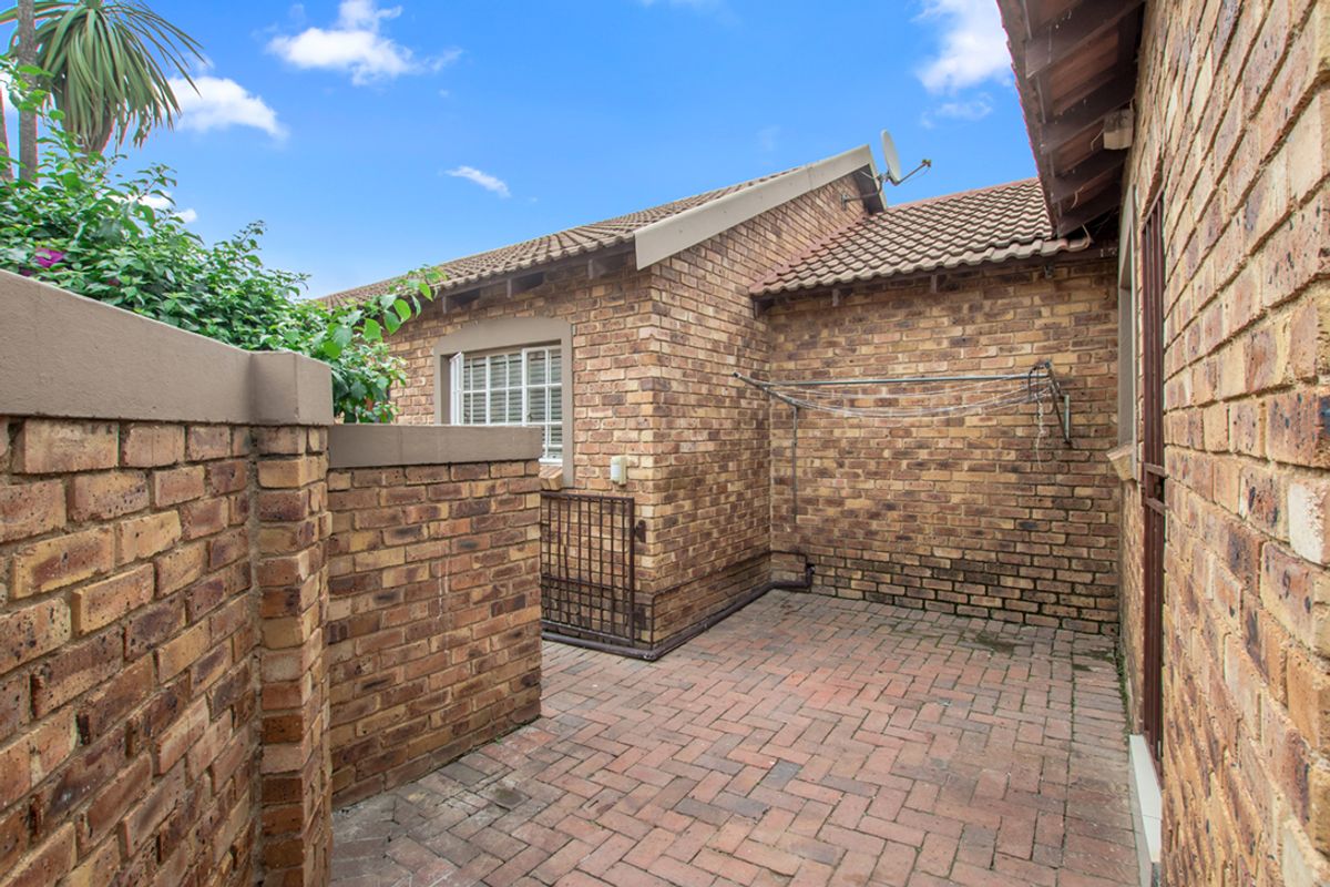 A private rear courtyard featuring brick paving, perimeter brick walls, and a wall-mounted clothes drying rack.