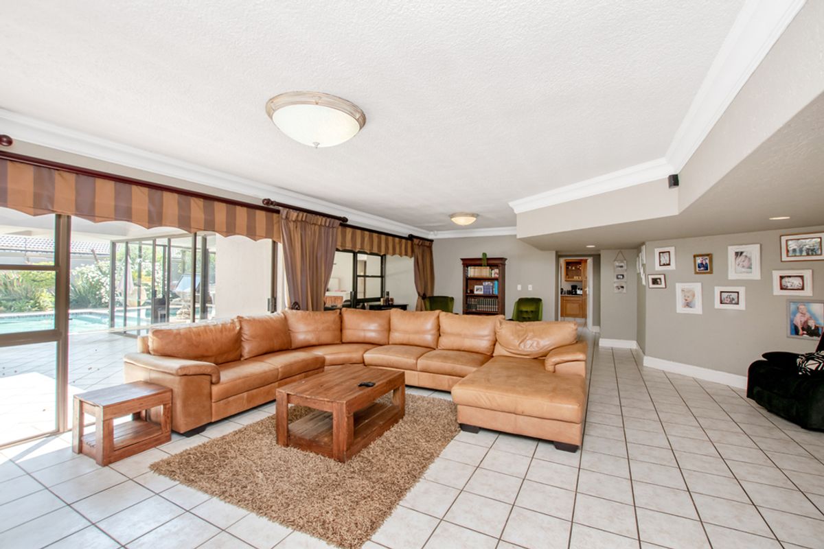 Spacious living room featuring large sliding glass doors that open to the pool area, ceramic tile flooring, and crown molding.