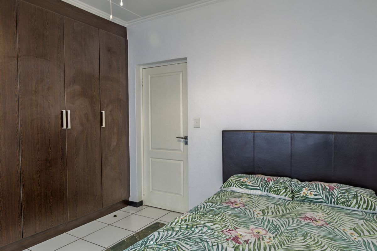 A bedroom featuring built-in dark wood cabinetry, tiled flooring, and a neutral wall finish.