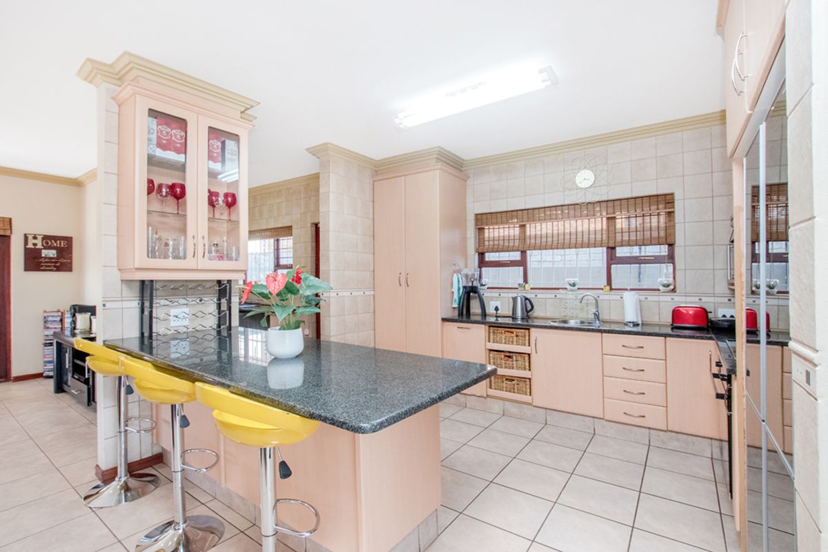 A functional kitchen featuring granite countertops, light-toned cabinetry, tiled flooring, and a breakfast bar island with integrated storage.