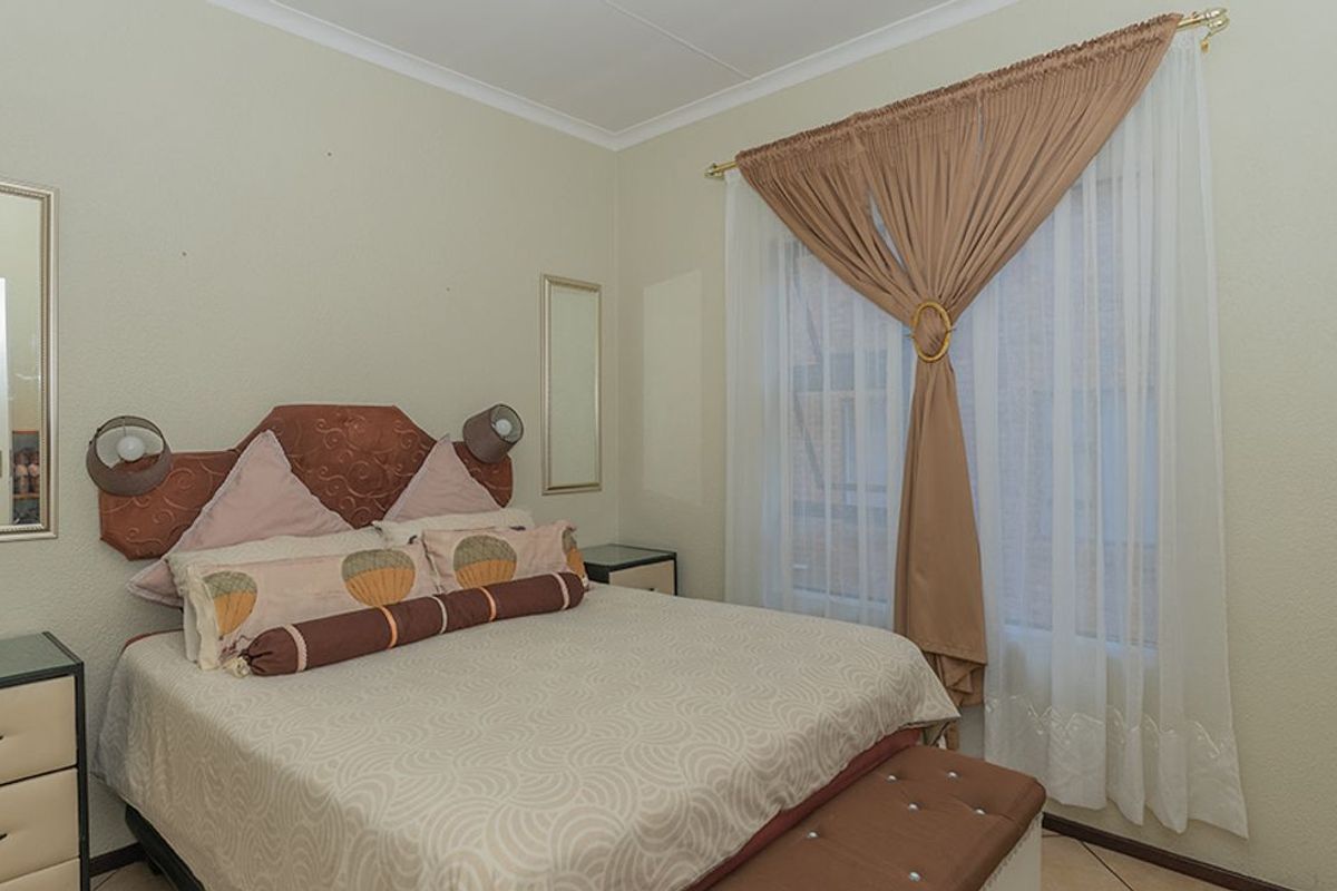 A standard bedroom featuring tiled flooring, neutral wall finishes, and a window with fitted curtain rods.