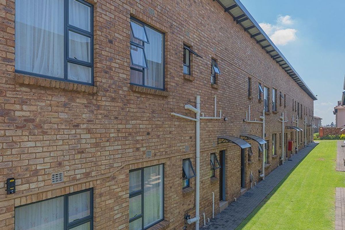 Exterior view of a multi-story apartment complex featuring face-brick facade, paved walkways, and well-maintained communal lawn areas.