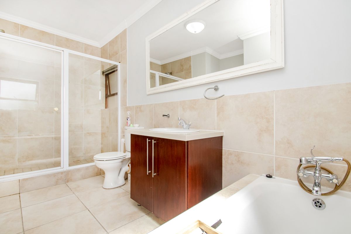 A well-maintained bathroom featuring a glass-enclosed shower, a built-in vanity with a basin, a toilet, and a bathtub with a handheld shower attachment.