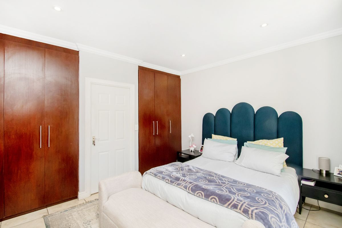 A well-maintained bedroom featuring built-in dark wood cabinetry, recessed ceiling lighting, and tiled flooring.
