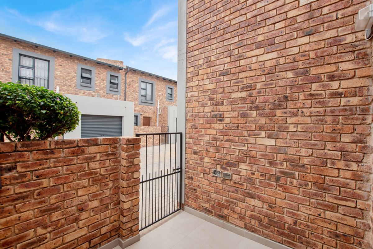 A view of the exterior brick facade and a small gated entrance area leading to the townhouse complex.
