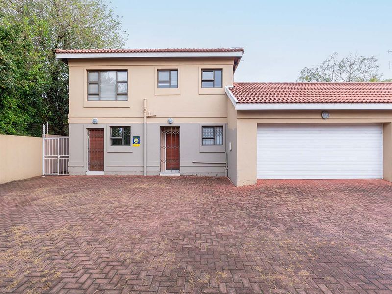 Front elevation of a two-story house featuring a paved driveway, double garage, and secure perimeter fencing.