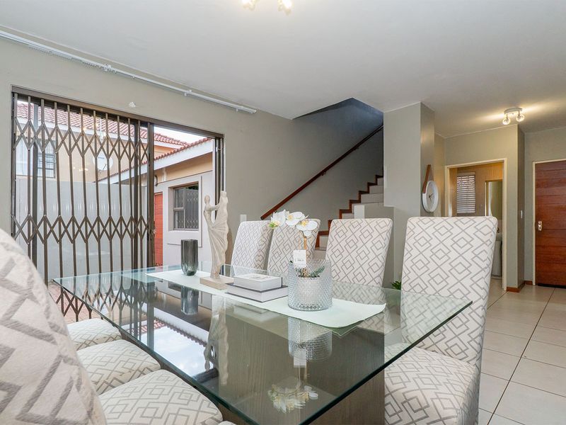 Dining area featuring tiled flooring, a staircase with a wooden handrail, and a sliding glass door leading to the exterior.