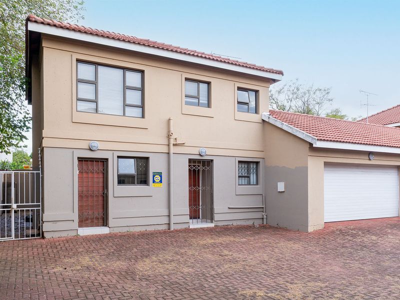 Front elevation of a two-story house featuring a paved driveway, integrated garage, and security-enhanced entry points with tiled roofing.