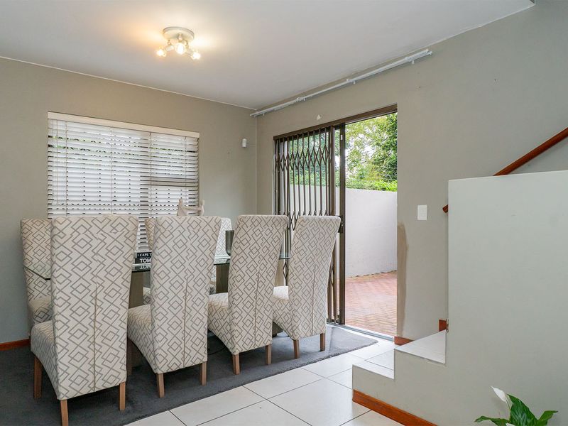 Dining area featuring tiled and carpeted flooring, sliding door access to the patio, and a staircase with a wooden handrail.