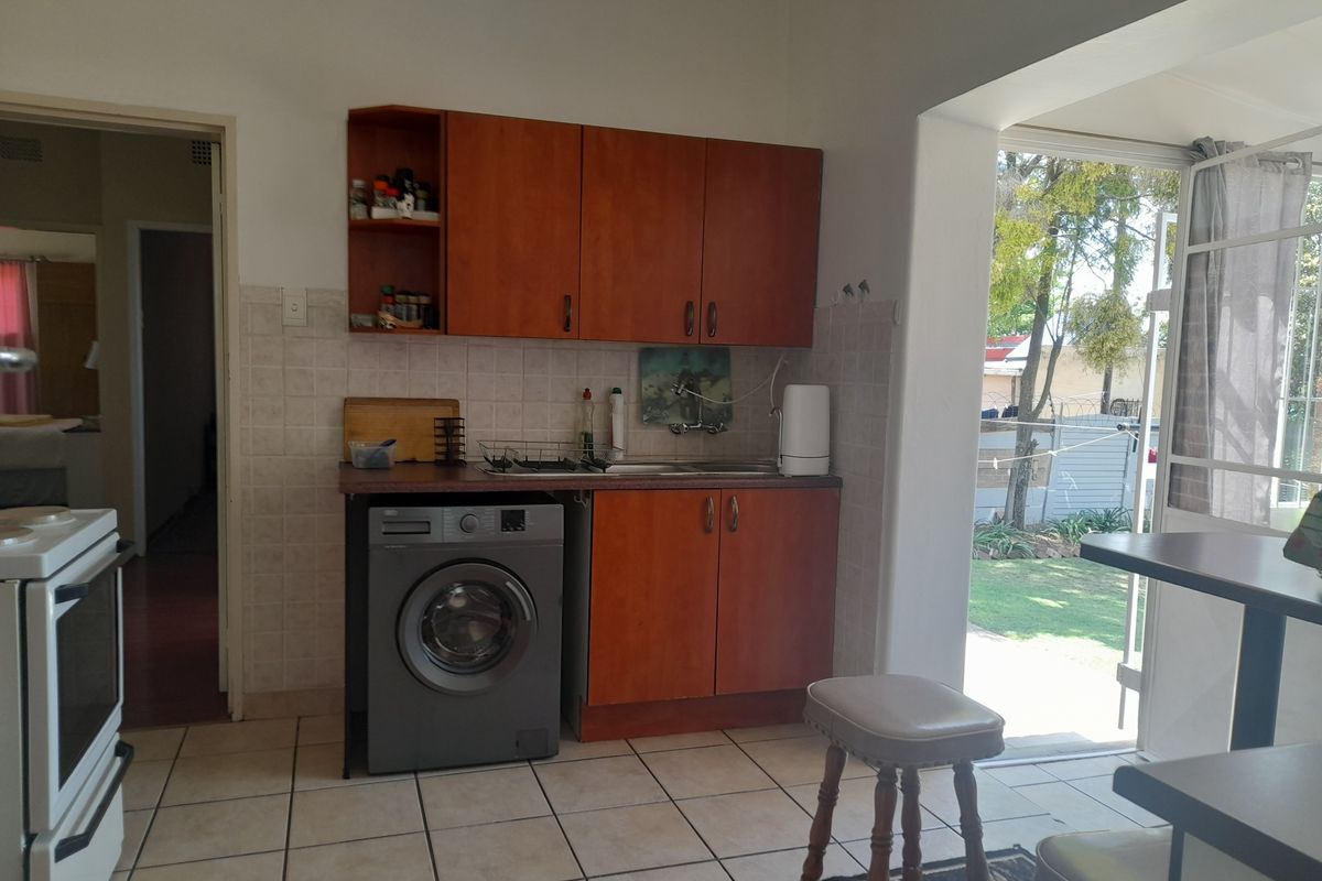 A functional kitchen area featuring wood-finish cabinetry, tiled backsplash, and direct access to the outdoor garden space.