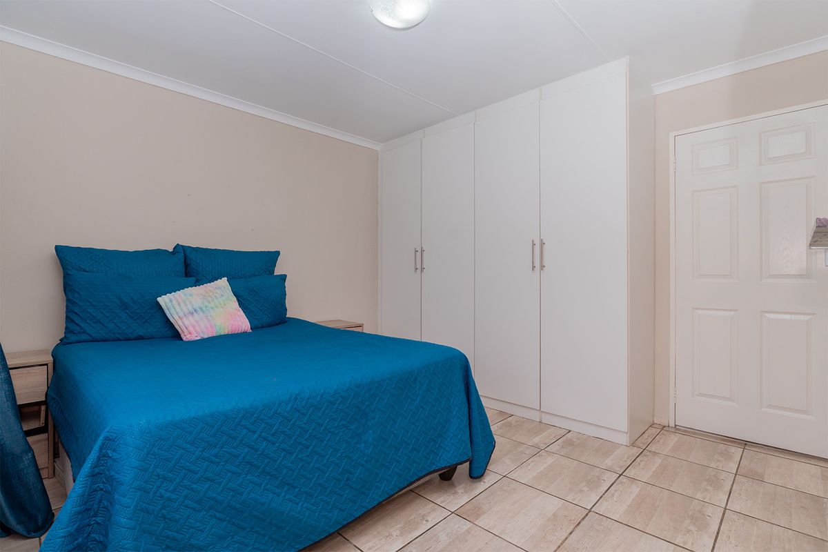 A bedroom featuring built-in white cabinetry and tiled flooring.