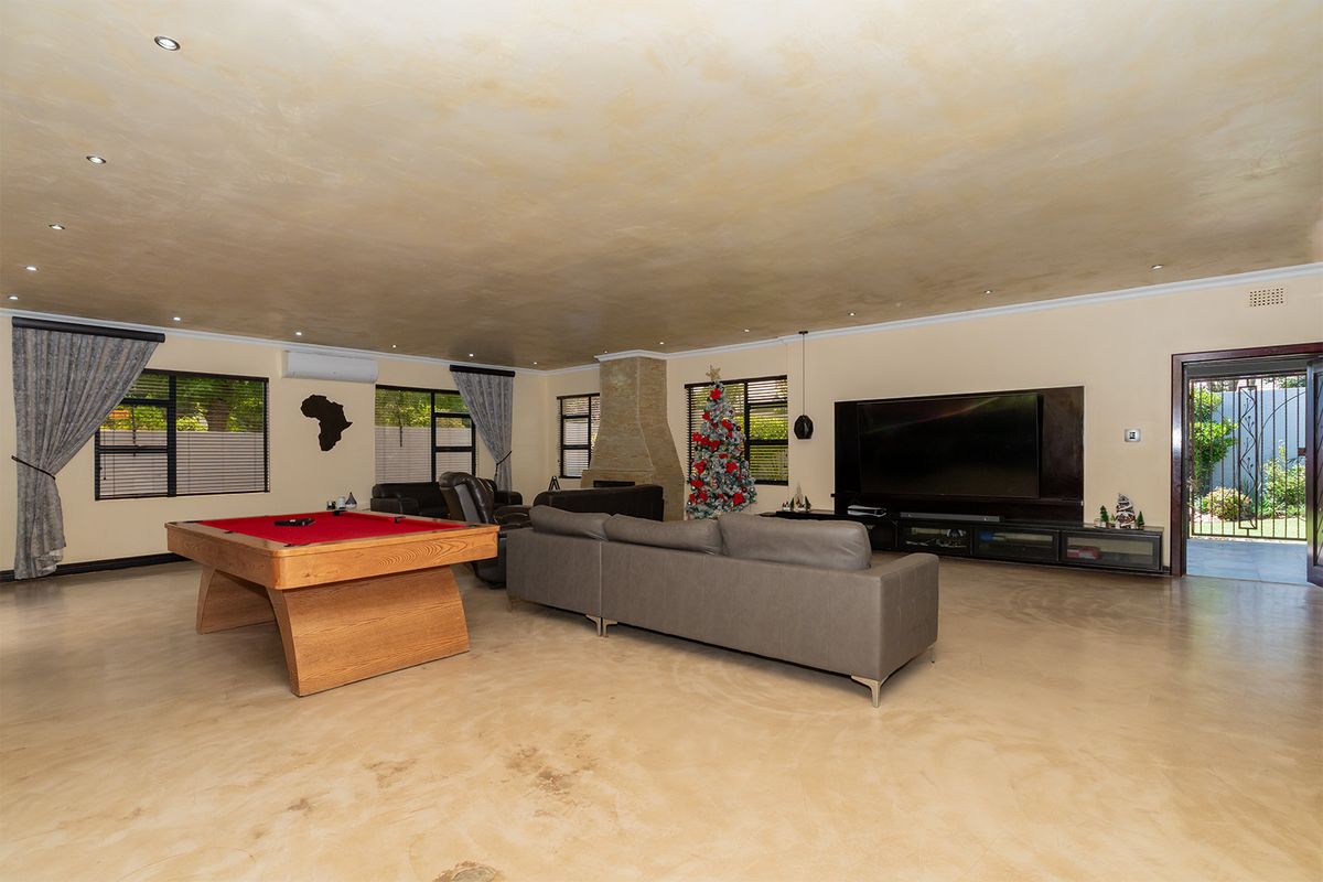 Spacious living area featuring a stone-clad fireplace, recessed ceiling lighting, and polished concrete flooring, offering a versatile space for relaxation and entertainment.