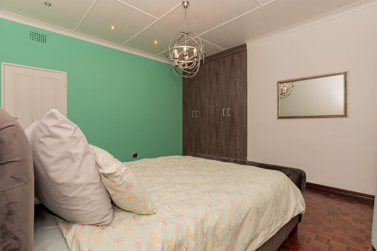 A bedroom featuring built-in wooden cupboards, parquet flooring, and a coffered ceiling with recessed lighting.